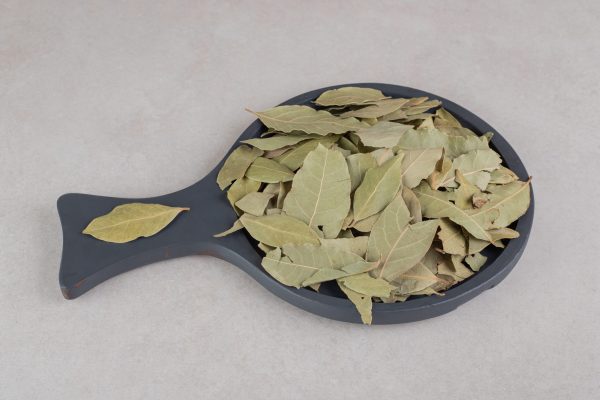 Dried green bay leaves on a wooden platter. High quality photo